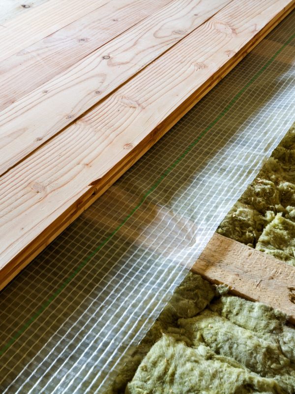 Installation of new floor of wooden natural planks and mineral wool insulation for isolation and keeping warmth. Modern technologies, warm comfortable house and eco-friendly insulation concept.